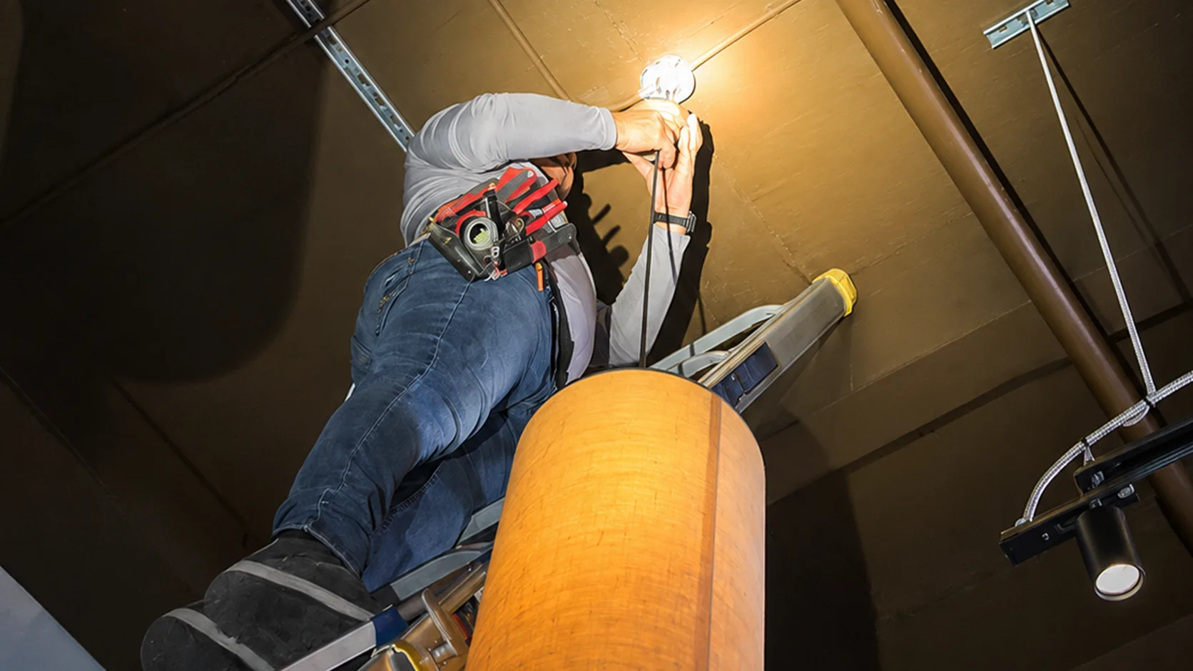 Electrician installing pendant lights in a Miami restaurant. Commercial lighting installation and electrical repairs in Miami.