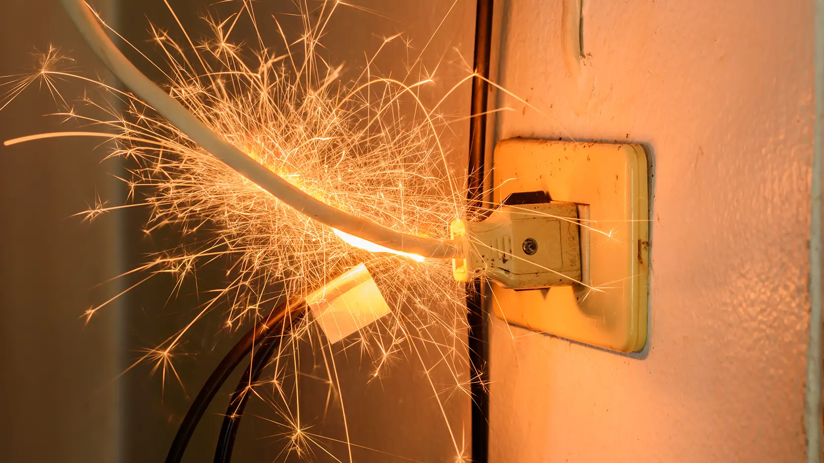 electrical-repair-4 Electrical outlet producing dangerous sparks due to a faulty plug connection, highlighting the risk of electrical shorts, overheating, and fire hazards.