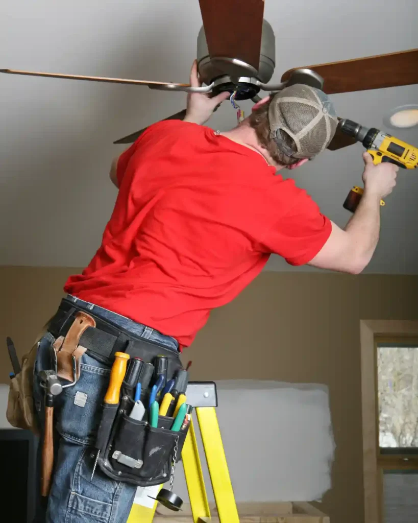 Electrician installing a ceiling fan in a residential property in Miami.